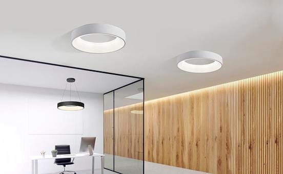 Plafon LED Sovana D80 CCT w kolorze białym, okrągły, montowany sufitowo, z pilotem. Widoczny w nowoczesnym biurze, na tle ściany z drewnianymi panelami. Oświetlenie o minimalistycznym designie, emitujące miękkie światło.