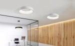Plafon LED Sovana D80 CCT w kolorze białym, okrągły, montowany sufitowo, z pilotem. Widoczny w nowoczesnym biurze, na tle ściany z drewnianymi panelami. Oświetlenie o minimalistycznym designie, emitujące miękkie światło.