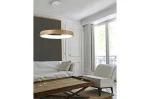 Lampa wisząca Silvam D45 LED w kształcie okręgu, z drewnianym obrzeżem i białym kloszem, zawieszona na cienkich linkach. Widok z góry, w jasnym pomieszczeniu z białymi ścianami i dużymi oknami. W tle sofa i drewniany stół z dwoma kieliszkami.