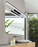 Kinkiet Epsilon 90 LED 4000K w kolorze czarnym, zamontowany nad lustrem w nowoczesnej łazience. Prosta, prostokątna forma, emitująca jasne światło, z widocznymi roślinami w tle. Kinkiet podkreśla elegancki design przestrzeni.
