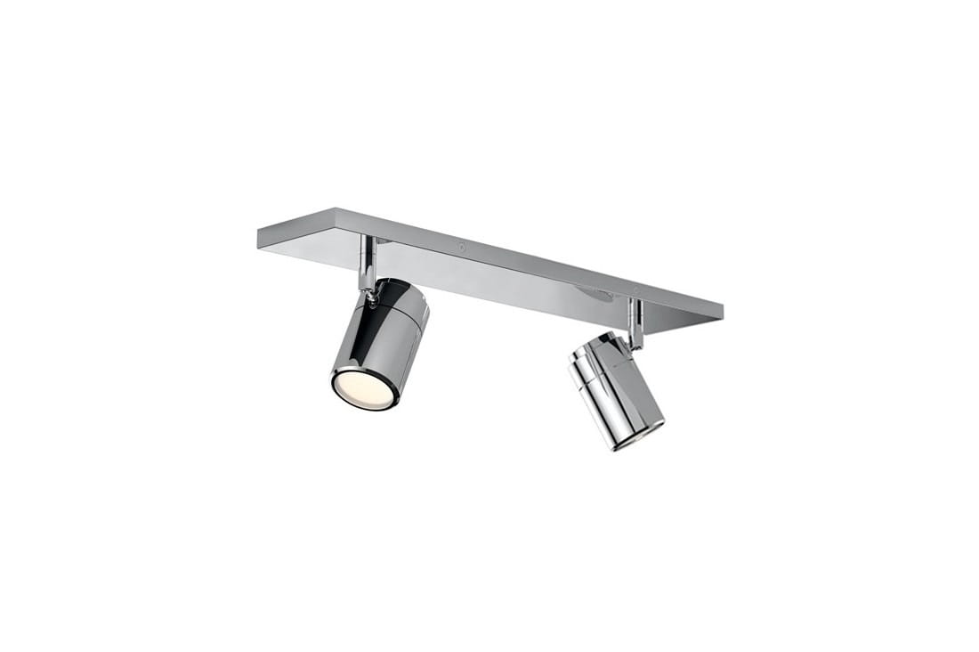 Lampa sufitowa Noemie IP44, 2-punktowa, z chromowaną podstawą. Dwa reflektory w cylindrycznym kształcie, zamocowane na prostokątnej płycie. Reflektory mogą być regulowane, co pozwala na kierowanie światła. Prosta konstrukcja na jednolitym tle.