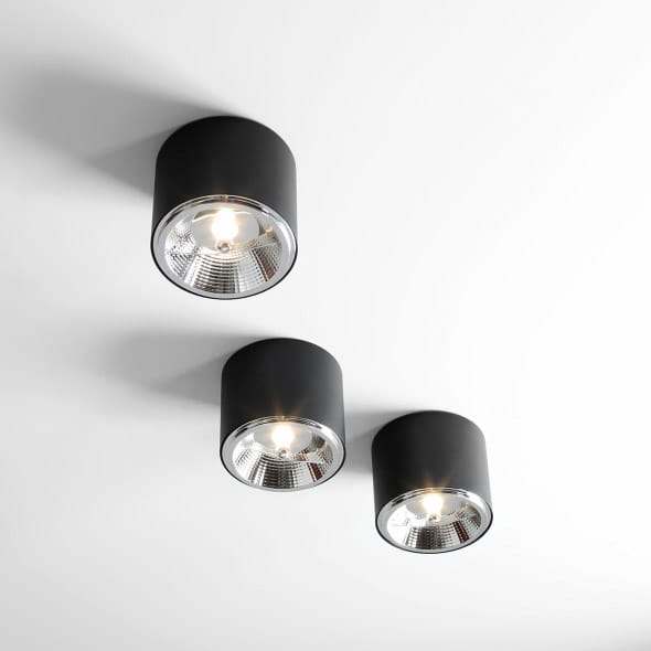 Lampa sufitowa spot 1-punktowa w kolorze czarnym, z okrągłym, matowym kloszem. Zainstalowane trzy źródła światła, zamontowane na białym suficie. Klosze mają metaliczne wykończenie, które podkreśla nowoczesny design.