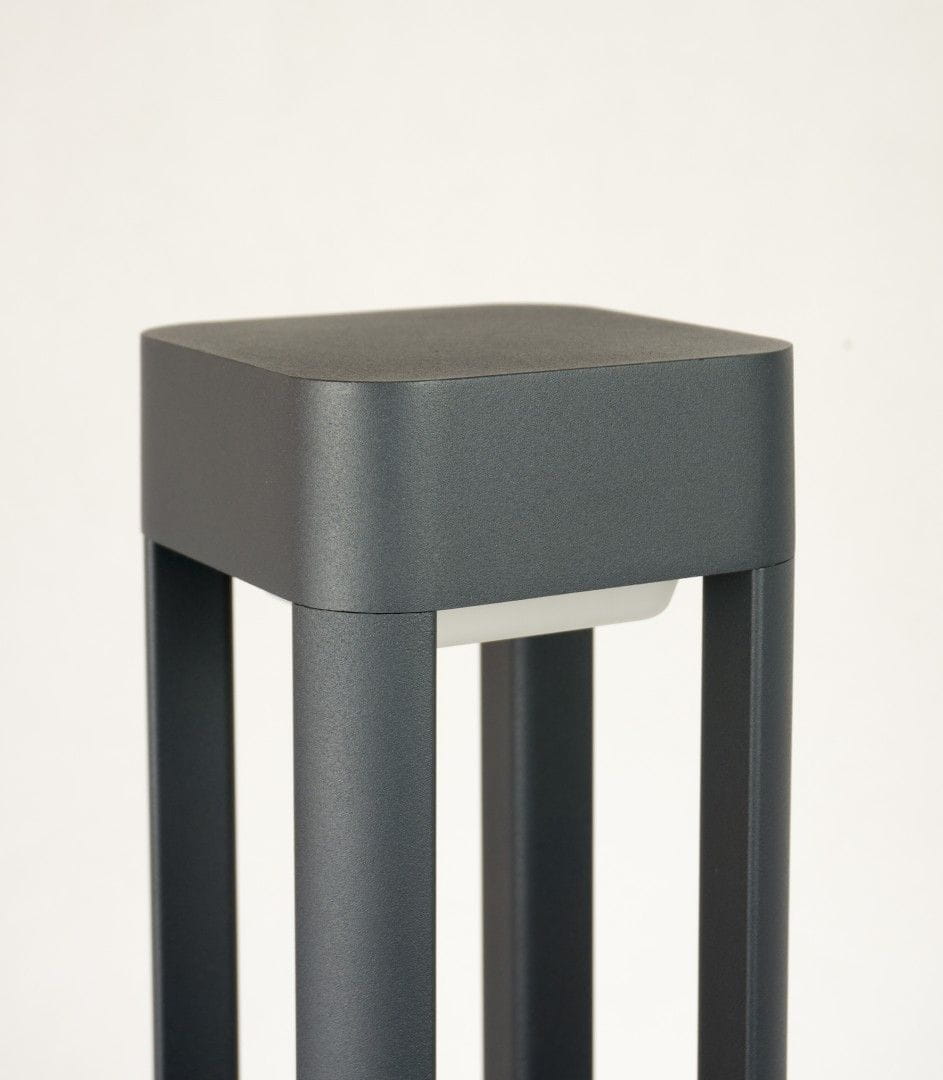 Lampa stojąca ogrodowa Fan Kwadrat H50, 1-punktowa, w kolorze grafitowym. Kwadratowa podstawa z metalowym wykończeniem, z prostymi nogami. Zbliżenie na górną część lampy, ukazujące jej minimalistyczny design. Tło jasne, jednolite.