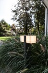 Lampa stojąca ogrodowa Cuba LED H75 w ciemnoszarym kolorze, dwupunktowa, z regulowanym kloszem. Ustawiona na tle zielonych traw, emituje ciepłe światło, tworząc przyjemną atmosferę w ogrodzie.