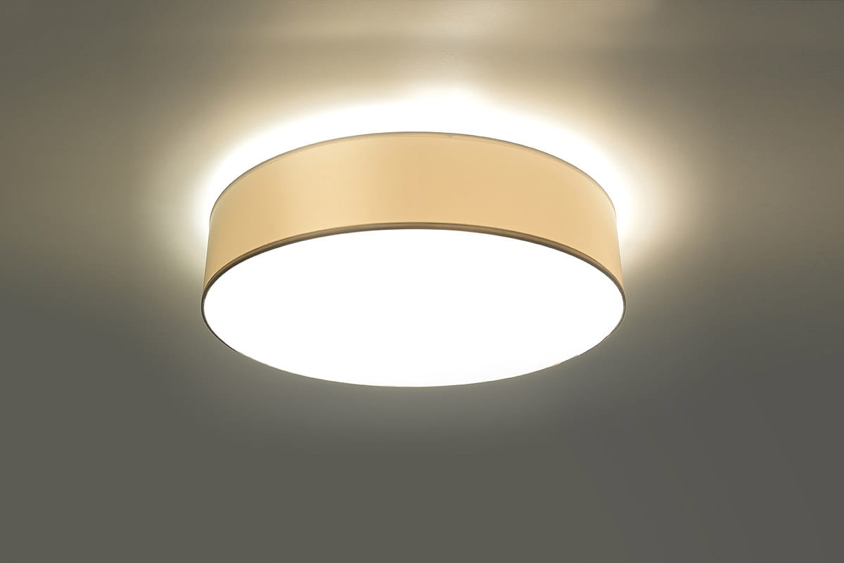 Biała lampa sufitowa Arena 25, okrągła, jednopunktowa. Wykonana z materiału z matowym wykończeniem, zamontowana na suficie, emitująca ciepłe światło. Krawędź lampy delikatnie podświetlona, co tworzy efekt rozproszonego blasku.