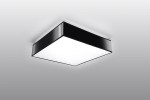 Lampa sufitowa Horus 25, 1-punktowa w kolorze czarnym, o kwadratowym kształcie. Ujęcie z dołu, pokazujące gładką, matową powierzchnię oraz jasną, emitującą światło część. Idealna do nowoczesnych wnętrz, zamontowana na prostym tle.