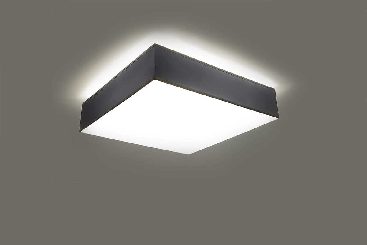 Lampa sufitowa Horus 25, 1-punktowa, w kolorze szarym. Prosta, kwadratowa forma z matowym białym kloszem, zamontowana na suficie, emitująca delikatne światło. Tło w odcieniu szaro-beżowym.