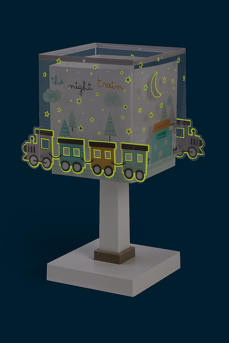 Lampka nocna Nocny Pociąg z przezroczystym kloszem ozdobionym ilustracjami pociągu, drzew, gwiazd i księżyca. Stojąca na prostokątnej podstawie, w kolorze białym, z brązowym akcentem. Klosz w kształcie sześcianu, podkreślający dziecięcy motyw.