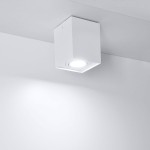 Biała lampa sufitowa kierunkowa Hadar z jedną oprawą GU10, w kwadratowej obudowie. Ujęcie z dołu, lampa zamontowana na suficie. Oświetlenie skierowane w dół, na gładkim, jasnym tle.