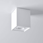 Lampa sufitowa Hadar w kolorze białym, z kwadratowym korpusem. Posiada jedno gniazdo GU10, zamontowana na suficie. Zbliżenie na okrągły element źródła światła, minimalistyczny design, idealna do nowoczesnych wnętrz.