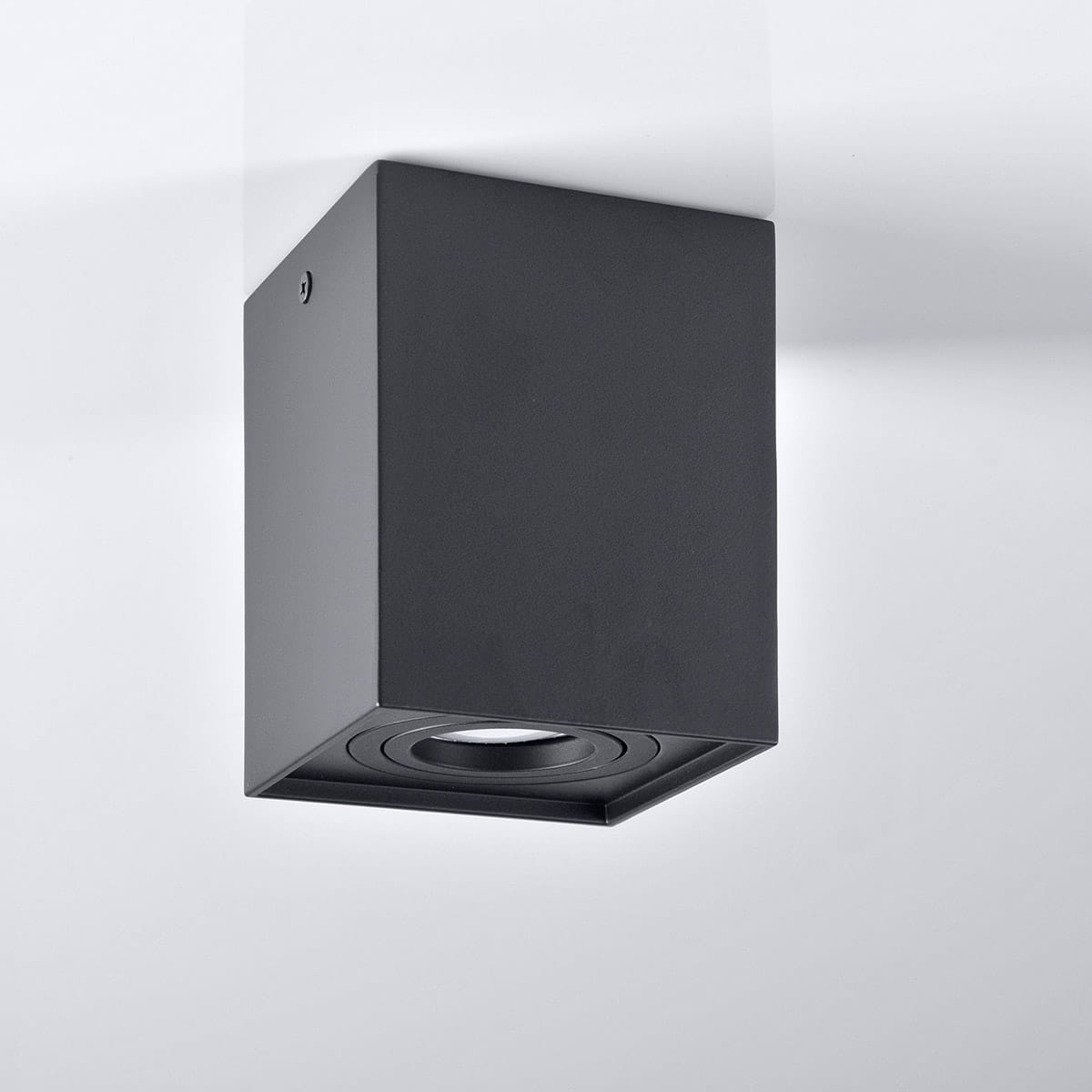 Lampa sufitowa kierunkowa Hadar w kolorze czarnym, z prostokątną obudową. Ujęcie z boku, ukazujące pojedyncze gniazdo na żarówkę GU10. Gładka, matowa powierzchnia, zamontowana na suficie, bez widocznych dekoracji.