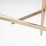 Lampa wisząca Tubo 6-punktowa w kolorze złotym, z widocznymi metalowymi rurkami tworzącymi strukturę. Kąt ujęcia z boku, ukazujący detal połączenia rur oraz jedno z miejsc na żarówkę. Tło jednolite, białe.