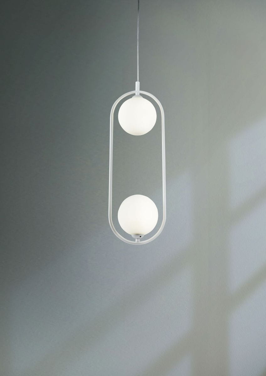 Lampa wisząca 2-punktowa w kolorze białym z okrągłymi kloszami. Produkt wisi na cienkim, przezroczystym przewodzie, z kloszami umieszczonymi w prostokątnej, metalowej ramie. Ujęcie frontalne na jednolitym tle.