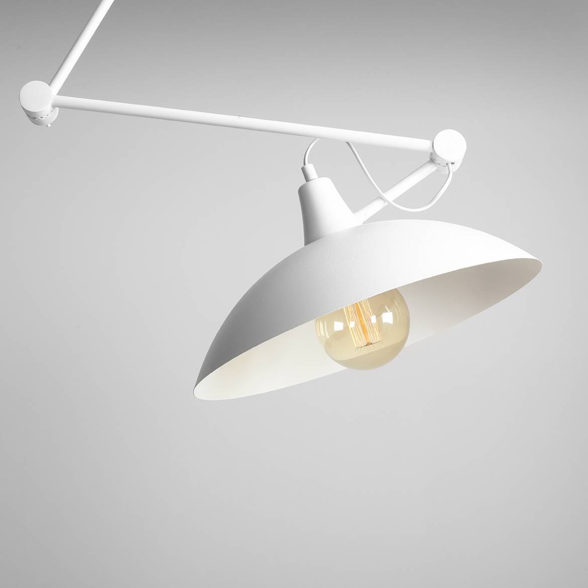 Lampa wisząca Melos 1-punktowa w kolorze białym, z okrągłym kloszem i widoczną żarówką. Ujęcie z boku, pokazujące zamontowaną konstrukcję i detale, takie jak metalowy uchwyt oraz estetyczne wykończenie klosza.