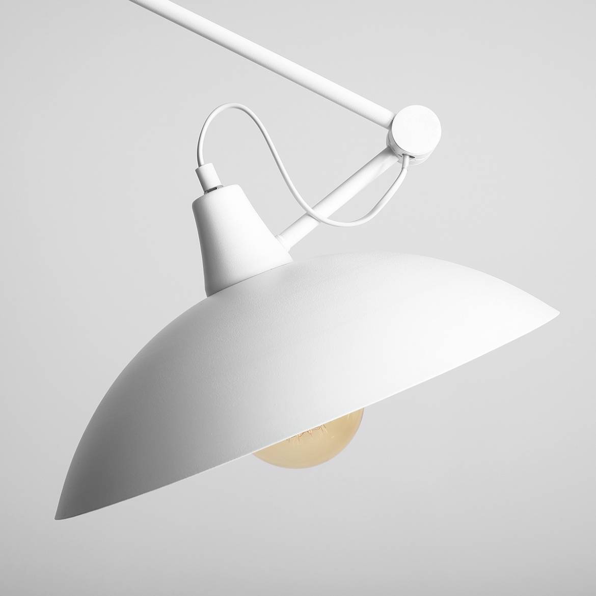 Lampa wisząca Melos 1-punktowa w kolorze białym, z metalowym, matowym kloszem w kształcie półkuli. Umieszczona na regulowanym ramieniu, widoczny kabel. Idealna do nowoczesnych wnętrz.
