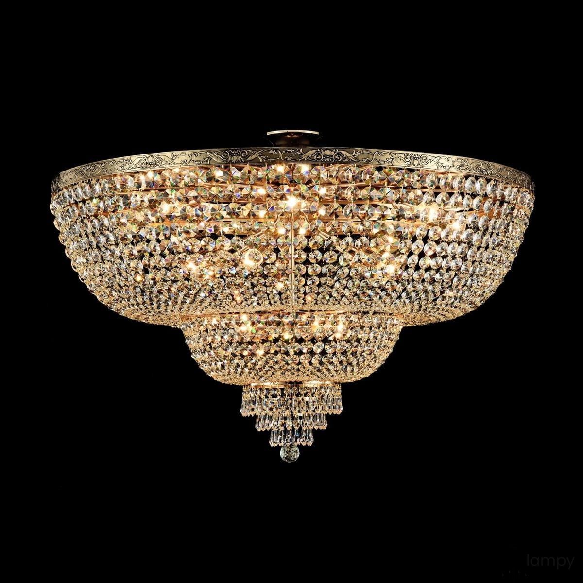 Lampa sufitowa Palace 18-punktowa, o okrągłym kształcie, z kryształowymi zdobieniami, w kolorze złotym. Zawiera wiele diod LED, które emitują jasne światło, umieszczona jest na ciemnym tle, co podkreśla jej elegancki wygląd.