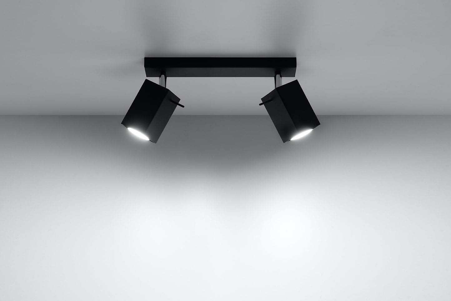 Czarna lampa sufitowa Merida 2-punktowa, składająca się z dwóch prostokątnych reflektorów zamocowanych na prostokątnej podstawie. Reflektory skierowane są w dół, na jednolitym tle. Lampa ma nowoczesny design, idealna do oświetlenia wnętrz.