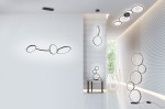 Czarna lampa sufitowa Rondo LED 4-punktowa z okrągłymi kloszami, zamontowana na prostokątnym stelażu. Widoczna w nowoczesnym wnętrzu, w towarzystwie innych lamp w formie okręgów na ścianach. Jasne tło podkreśla minimalistyczny design.