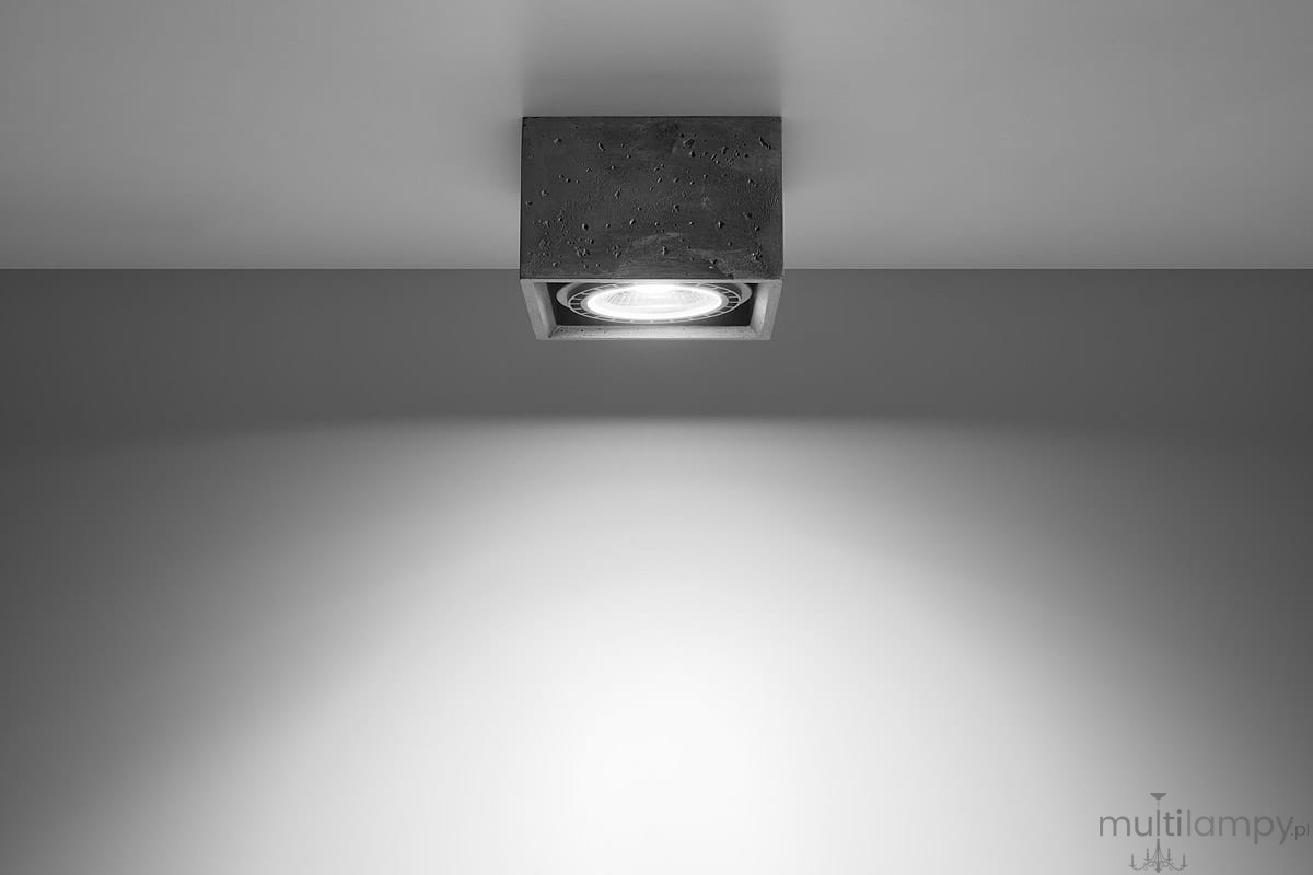 Lampa sufitowa Quatro 1-punktowa w kolorze szarym, wykonana z betonu. Kwadratowa forma z widoczną oprawą świetlną w centrum. Ujęcie z dołu, montowana na suficie, otoczenie w jednolitym tle.
