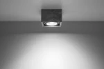 Lampa sufitowa Quatro 1-punktowa w kolorze szarym, wykonana z betonu. Kwadratowa forma z widoczną oprawą świetlną w centrum. Ujęcie z dołu, montowana na suficie, otoczenie w jednolitym tle.