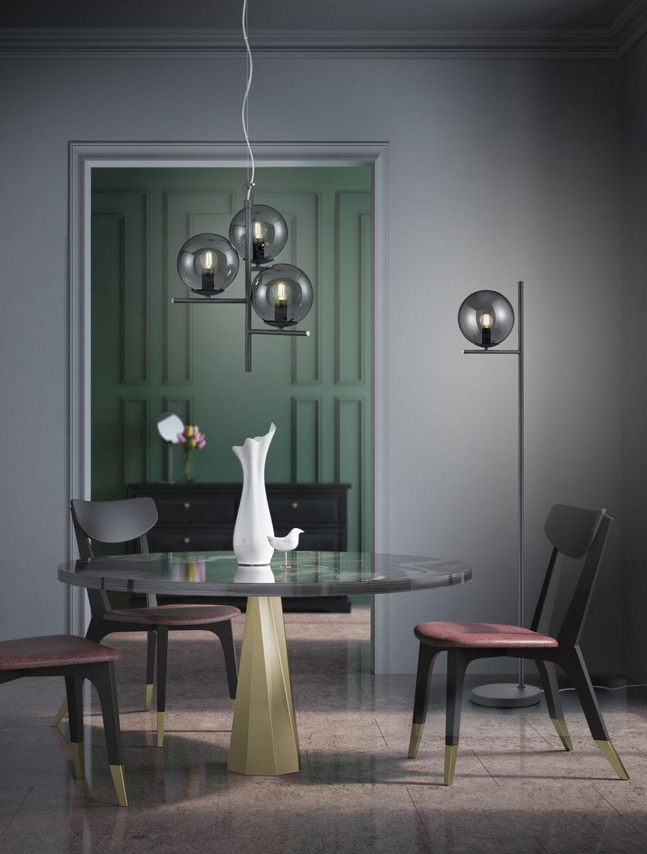 Lampa wisząca Pure 3-punktowa w kolorze antracytowym z trzema szklanymi kloszami w odcieniu ciemnego szkła, zawieszona nad okrągłym stołem z metalową podstawą w złotym kolorze, w nowoczesnym wnętrzu.