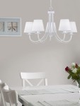 Lampa wisząca Cortez 5-punktowa w kolorze białym. Posiada pięć kloszy w formie stożków, umieszczonych na eleganckich ramionach. Zawieszona na łańcuchu, idealna do aranżacji jadalni. Tło w odcieniach szarości z białymi meblami i bukietem kwiatów.