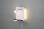 Kinkiet LED w kolorze białym z portem USB, z zamontowanym kloszem w ruchomej pozycji oraz małą półką na telefon. Oświetlenie z tyłu emituje ciepłe światło, a całość jest przymocowana do szarej ściany.