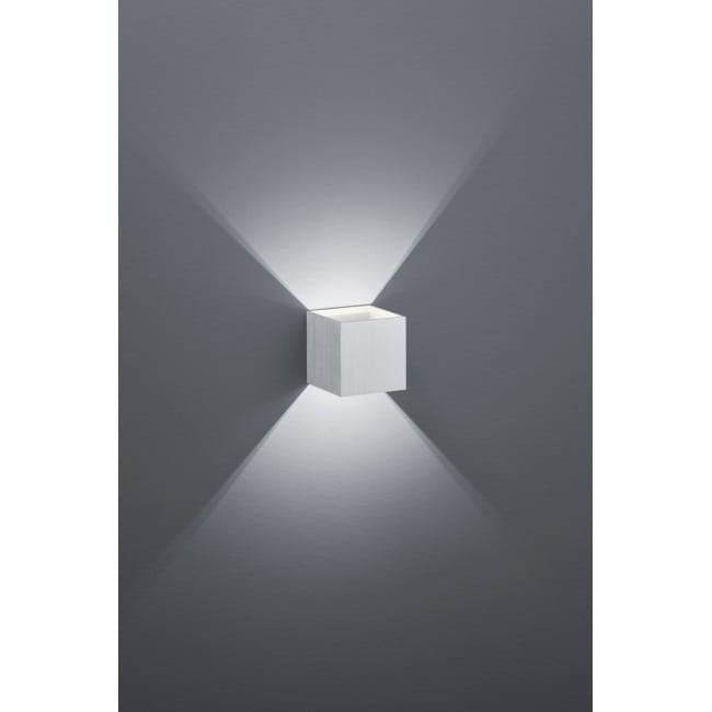 Kinkiet LED Louis w kolorze aluminium, o prostokątnym kształcie, zamontowany na szarej ścianie. Emituje światło w dwóch kierunkach, tworząc efekt świetlny. Produkt ma matową fakturę, jest nowoczesny i minimalistyczny.