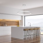 Lampa wisząca Circle LED D110 w kolorze białym, o okrągłym kształcie, zawieszona na cienkich linkach. Widoczna w nowoczesnej kuchni z jasnymi meblami i drewnianą dekoracją. Oświetlenie centralne nad stołem barowym z krzesłami.