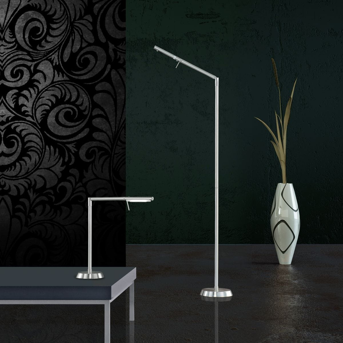 Filigran LED lampa podłogowa 1-punktowa w kolorze nikiel, z cienką, prostą konstrukcją oraz okrągłą podstawą. Ujęcie z boku, obok mniejsza lampa biurkowa. Tło z dekoracyjnym wzorem i gładką, ciemną ścianą.