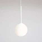 Lampa wisząca Bosso D14 o białym, okrągłym kloszu wykonanym z matowego materiału. Zawieszona na cienkim, białym przewodzie. Prosta forma, idealna do nowoczesnych wnętrz. Tło w jasnym odcieniu, podkreślające elegancję lampy.