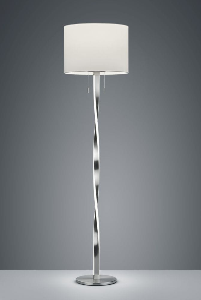Lampa podłogowa Nandor E27 w kolorze niklowym z białym abażurem. Posiada trzy punkty świetlne i smukłą, falującą podstawę. Ujęcie frontalne, produkt stoi na płaskiej powierzchni, w tle ciemnoszare.