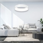 Biała lampa wisząca Ohio LED o okrągłym kształcie, zawieszona nad nowoczesnym, jasnym wnętrzem. Lampa emituje równomierne światło, a w tle widoczna jest szara sofa, stół kawowy oraz roślina doniczkowa.