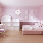 Plafon LED Sweet Pink w kształcie kota, biały z różowymi akcentami, zamontowany na różowej, kratkowanej ścianie. W otoczeniu mebli dziecięcych w jasnych kolorach, w tym biurka i łóżka z białą pościelą.