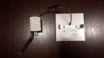 Oprawa schodowa Lumi White LED 230V z ciepłą barwą światła 3000K. Widoczny jest metalowy korpus z logo E-light oraz zasilacz. Kable w kolorach czarnym, brązowym i niebieskim są podłączone do zasilacza. Produkt leży na drewnianej powierzchni.