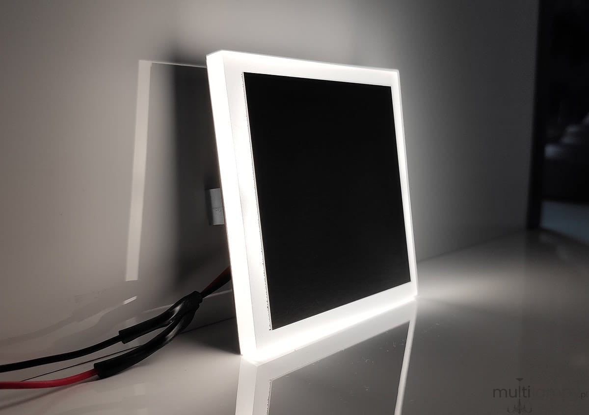 Evo Black LED oprawa schodowa 230V z neutralnym światłem 4000K, kwadratowa, z czarnym wnętrzem i białą ramką. Ujęcie z boku, widoczne przewody zasilające. Produkt w pozycji stojącej na gładkiej powierzchni.