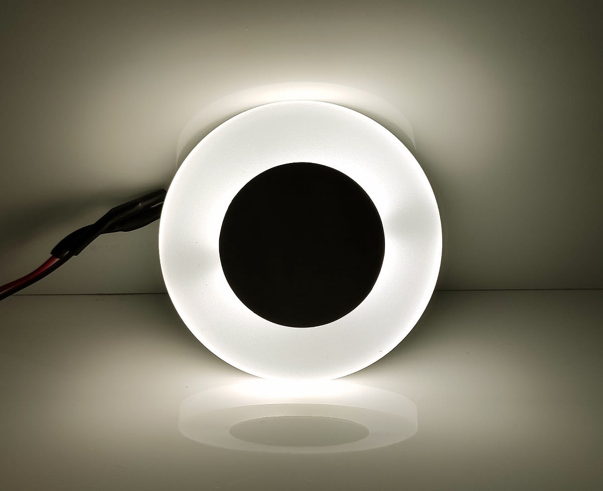 Oti Black LED oprawa schodowa 230V w kształcie okręgu, z matowym białym obrzeżem i czarnym środkiem. Źródło światła o barwie neutralnej 4000K, montowana na ścianie lub w podłodze. Widoczny przewód zasilający.