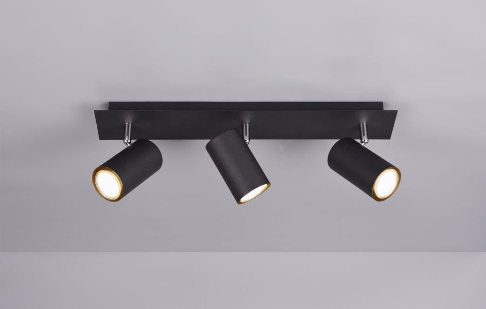 Trzypunktowa lampa sufitowa Marley w kolorze czarnym, z cylindrycznymi kloszami zewnętrznymi, wewnątrz złote, zamontowana na prostokątnej czarnej podstawie. Klosze skierowane w różne strony, montowana na suficie, na jednolitym tle.