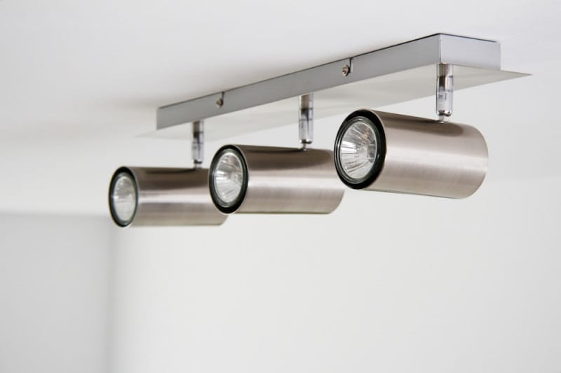 Lampa sufitowa Marley, 3-punktowa, w kolorze niklu. Składa się z trzech cylindrycznych reflektorów zamocowanych na prostokątnej, metalowej podstawie. Reflektory są w kierunku frontalnym, na jednolitym tle.
