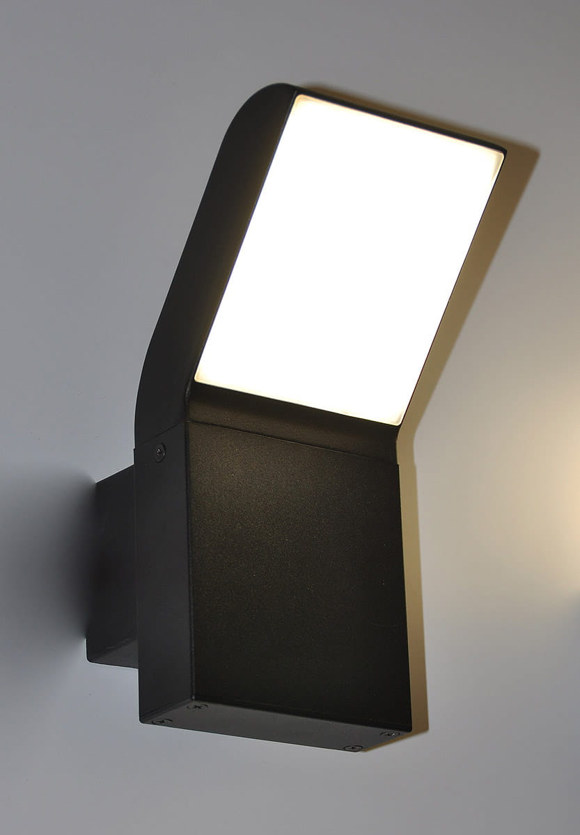 Kinkiet zewnętrzny Vidar LED, czarny, 1-punktowy. Montowany na ścianie, z prostokątną, białą kloszem i matową powierzchnią. Widok z boku, podkreślający kąt ułożenia klosza. Brak widocznych napisów czy logo.
