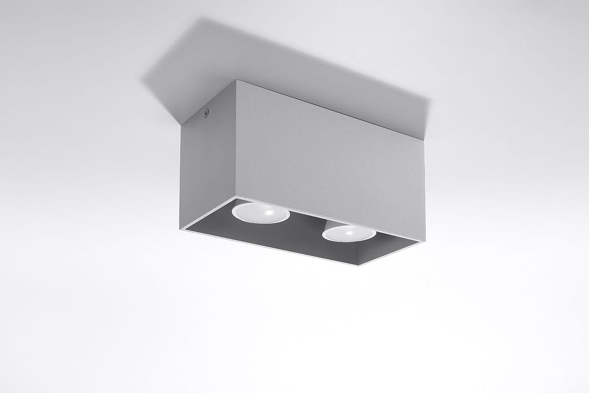 Lampa sufitowa Quad Maxi 2-punktowa w kolorze szarym, kwadratowa obudowa z matowego metalu. Ujęcie z boku, widoczne dwa okrągłe źródła światła w dolnej części. Brak dekoracji, minimalistyczny design, montowana na suficie.