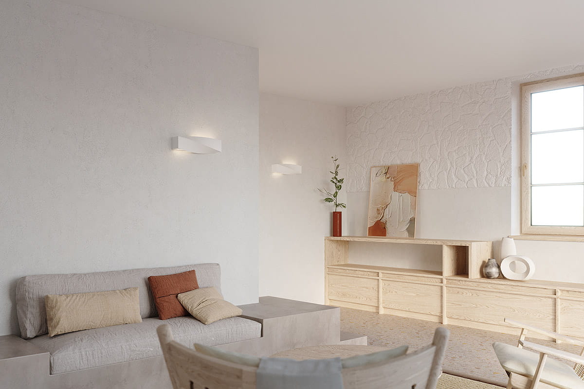 Kinkiet Sigma 1-punktowy ceramiczny w kolorze białym, o nowoczesnym, prostokątnym kształcie, zamontowany na jasnej ścianie. W tle widoczny stół z naturalnego drewna oraz sofy z poduszkami w neutralnych odcieniach.