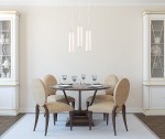 Lampa wisząca Nancy 1-punktowa, ceramiczna, w kształcie cylindrycznym. Zawieszona nad okrągłym stołem w jadalni, w białym kolorze, z trzema źródłami światła. Otoczenie z jasnymi meblami oraz beżowymi krzesłami z okrągłymi oparciami.