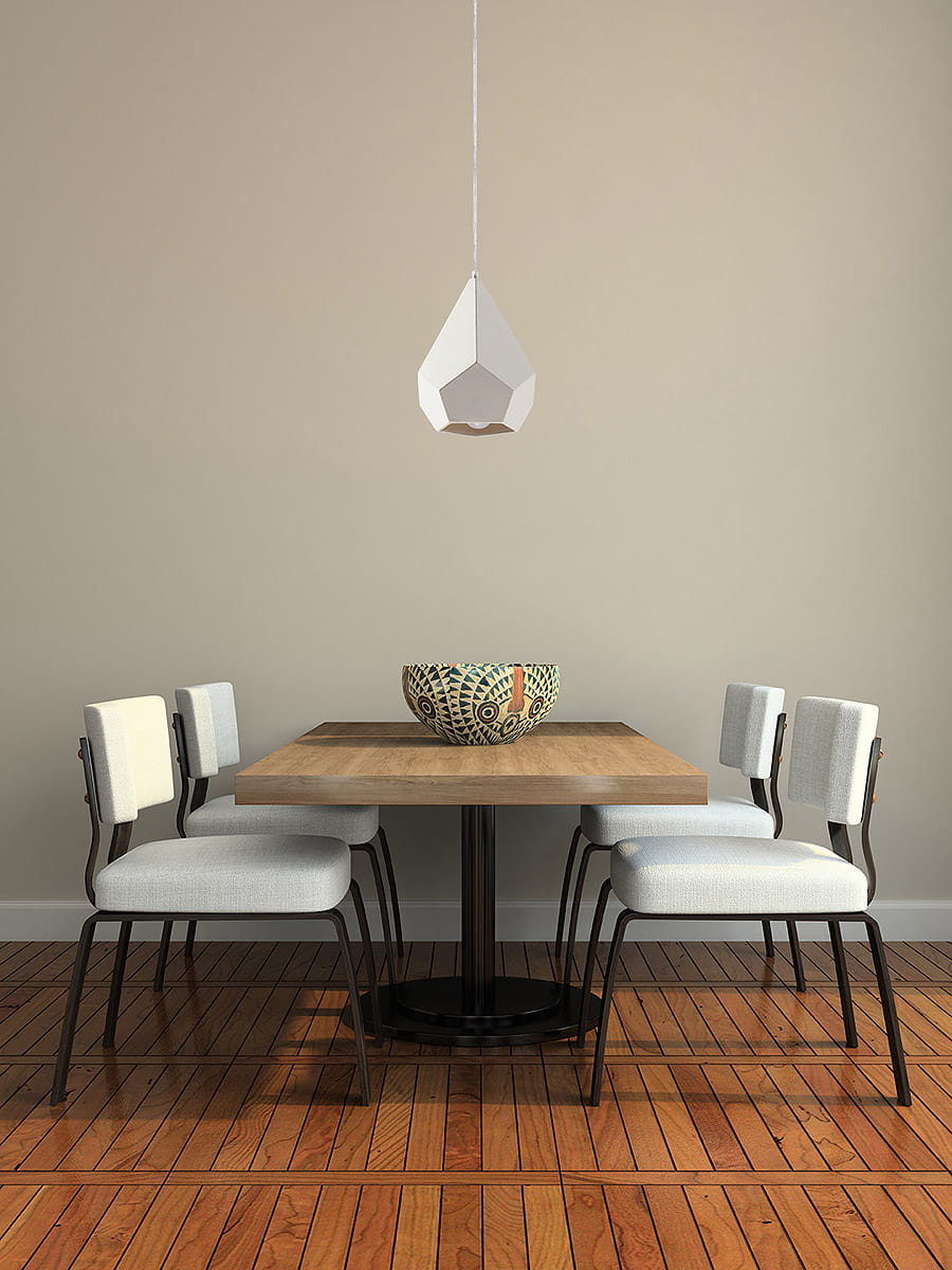Lampa wisząca Pavlus 1-punktowa, ceramiczna, w kształcie stożka, w kolorze białym, zawieszona nad drewnianym stołem z czarną podstawą. W tle cztery krzesła z jasnoszarymi siedziskami i ozdobna miska na stole.