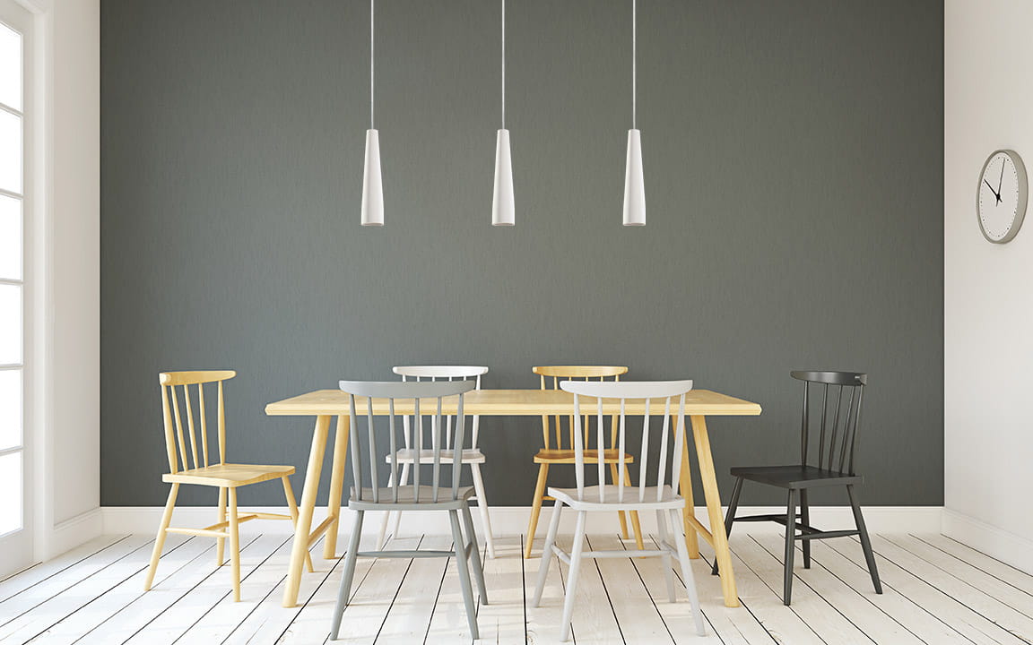 Lampa wisząca Electra, ceramiczna, biała, z jednym gniazdem GU10, zawieszona na cienkim przewodzie. Widoczna w nowoczesnej jadalni z drewnianym stołem i kolorowymi krzesłami na tle szarej ściany.