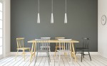 Lampa wisząca Electra, ceramiczna, biała, z jednym gniazdem GU10, zawieszona na cienkim przewodzie. Widoczna w nowoczesnej jadalni z drewnianym stołem i kolorowymi krzesłami na tle szarej ściany.
