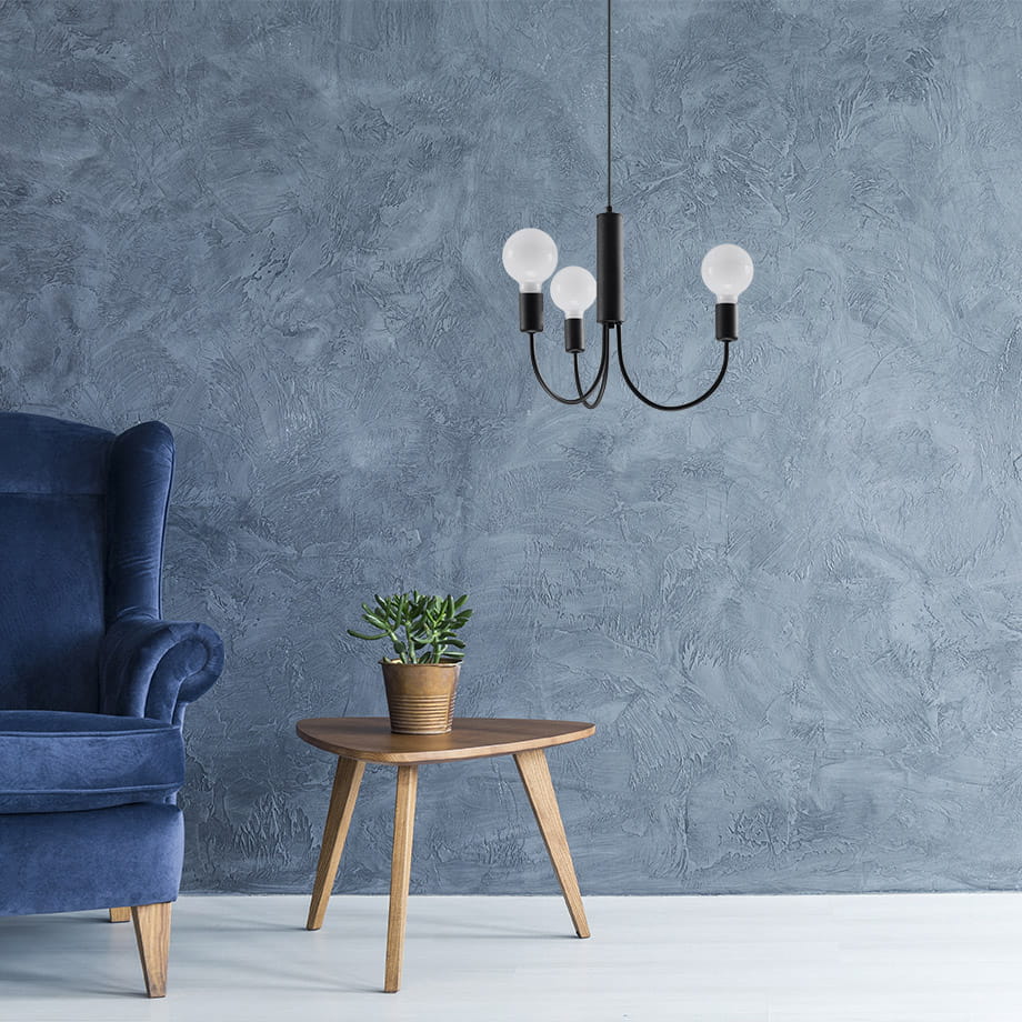 Lampa wisząca Piccolo 3-punktowa SL.0856 w czarnej oprawie z trzema kulistymi, białymi kloszami. Zawieszona na cienkim przewodzie, w aranżacji z niebieskim fotelem i drewnianym stolikiem z doniczką. Tło w odcieniach szarości.