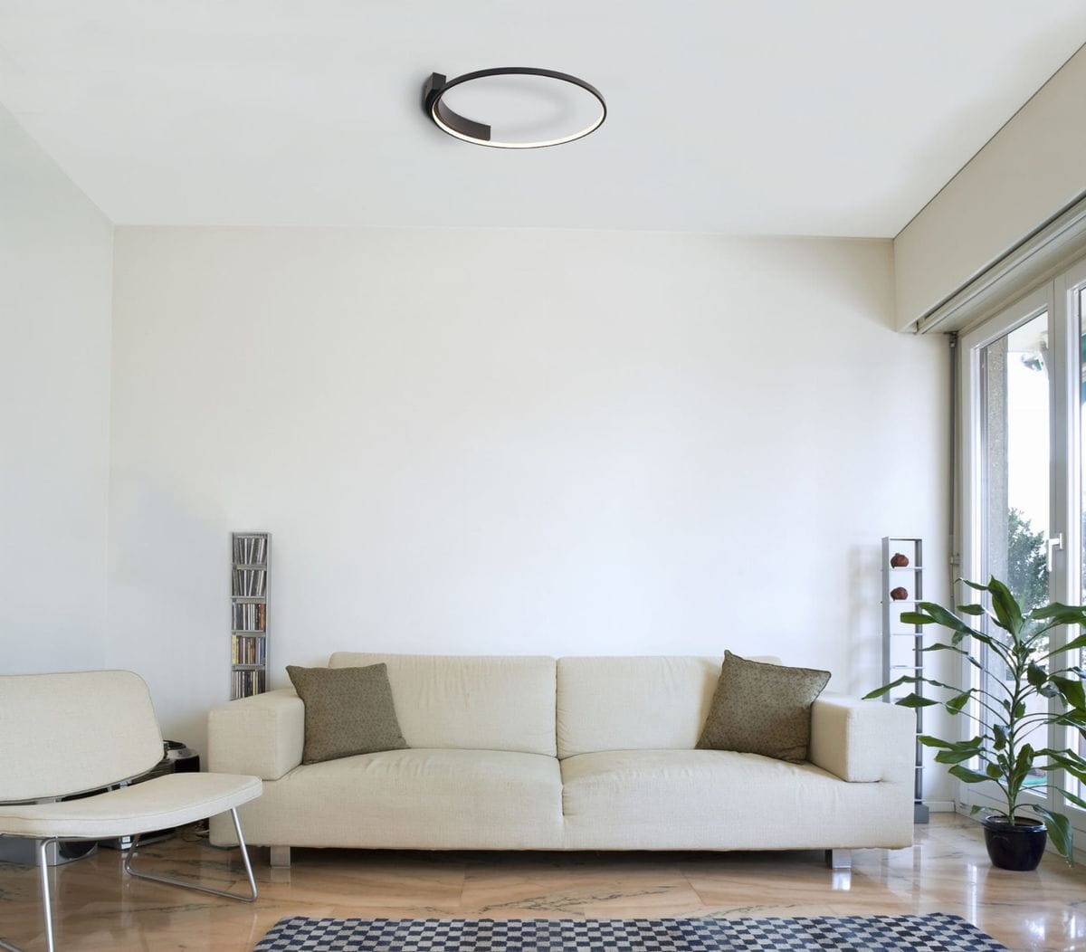 Velvet LED lampa sufitowa 1-punktowa w okrągłej, cienkiej oprawie w kolorze czarnym z delikatnym, białym światłem. Zawieszona na suficie, w otoczeniu jasnej ściany oraz mebli w nowoczesnym wnętrzu.
