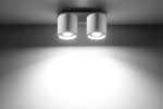 Lampa sufitowa Orbis 2-punktowa w kolorze białym, z dwoma cylindrycznymi kloszami zamocowanymi na płaskiej podstawie. Ujęcie frontalne, pokazujące źródła światła, na jednolitym tle, z wyraźnym oświetleniem.