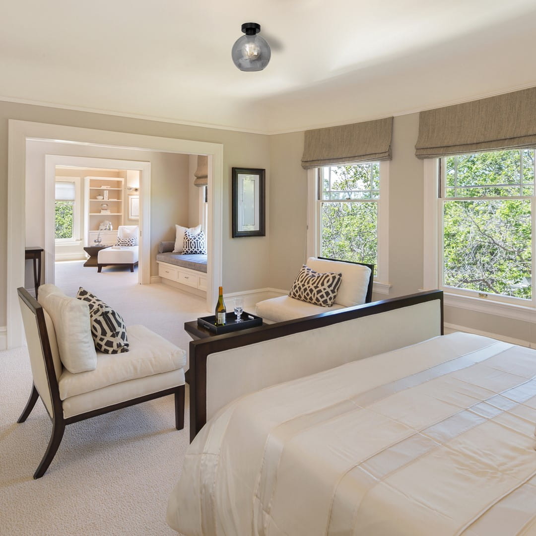 Lampa sufitowa Sofia 1-punktowa, dymiona, z okrągłym kloszem, zamontowana na suficie. W tle widoczny nowoczesny pokój dzienny z jasnymi ścianami, oknami i meblami w neutralnych kolorach.